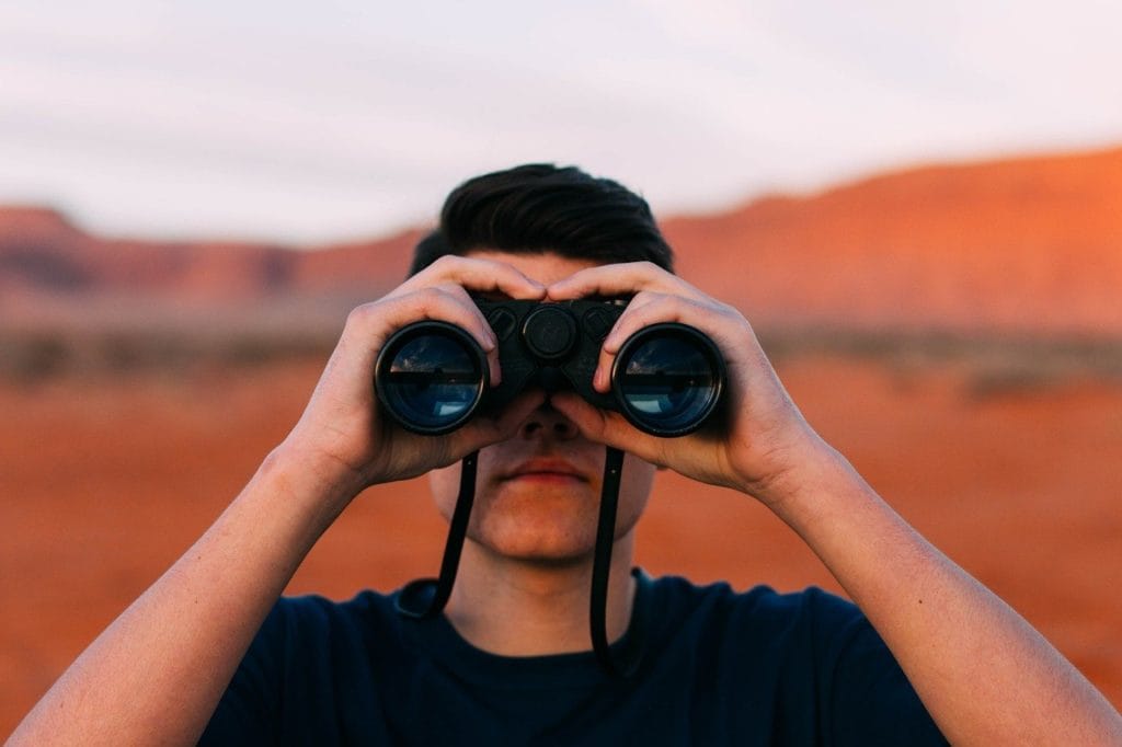 Man looking into the distance with binoculars indicating the future of global health work.