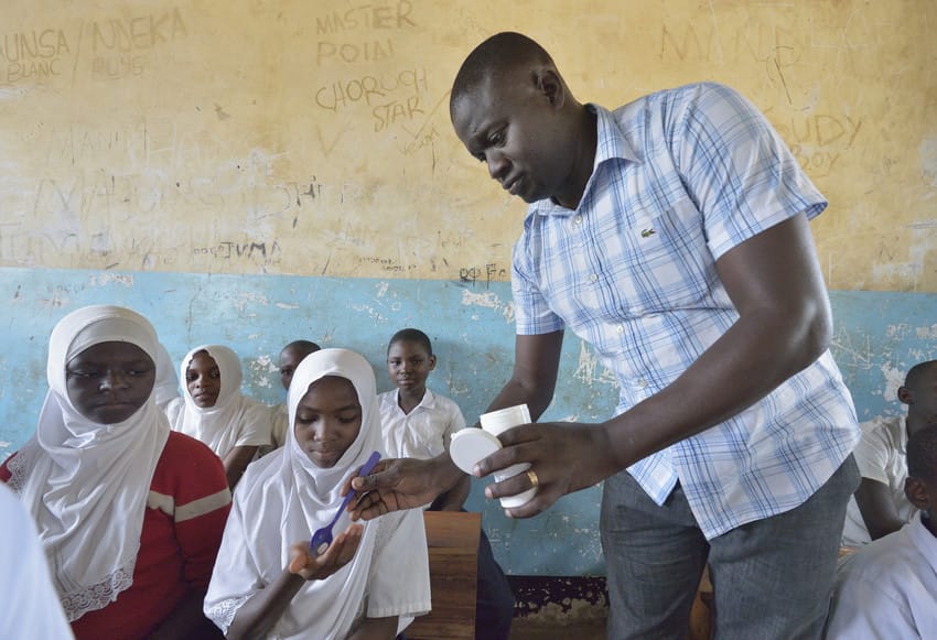 A man distributes medicine to fight neglected tropical diseases to students in Tanzania.