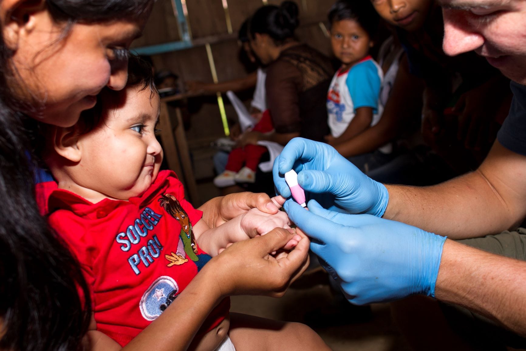 A health worker draws blood to test a child for anemia.