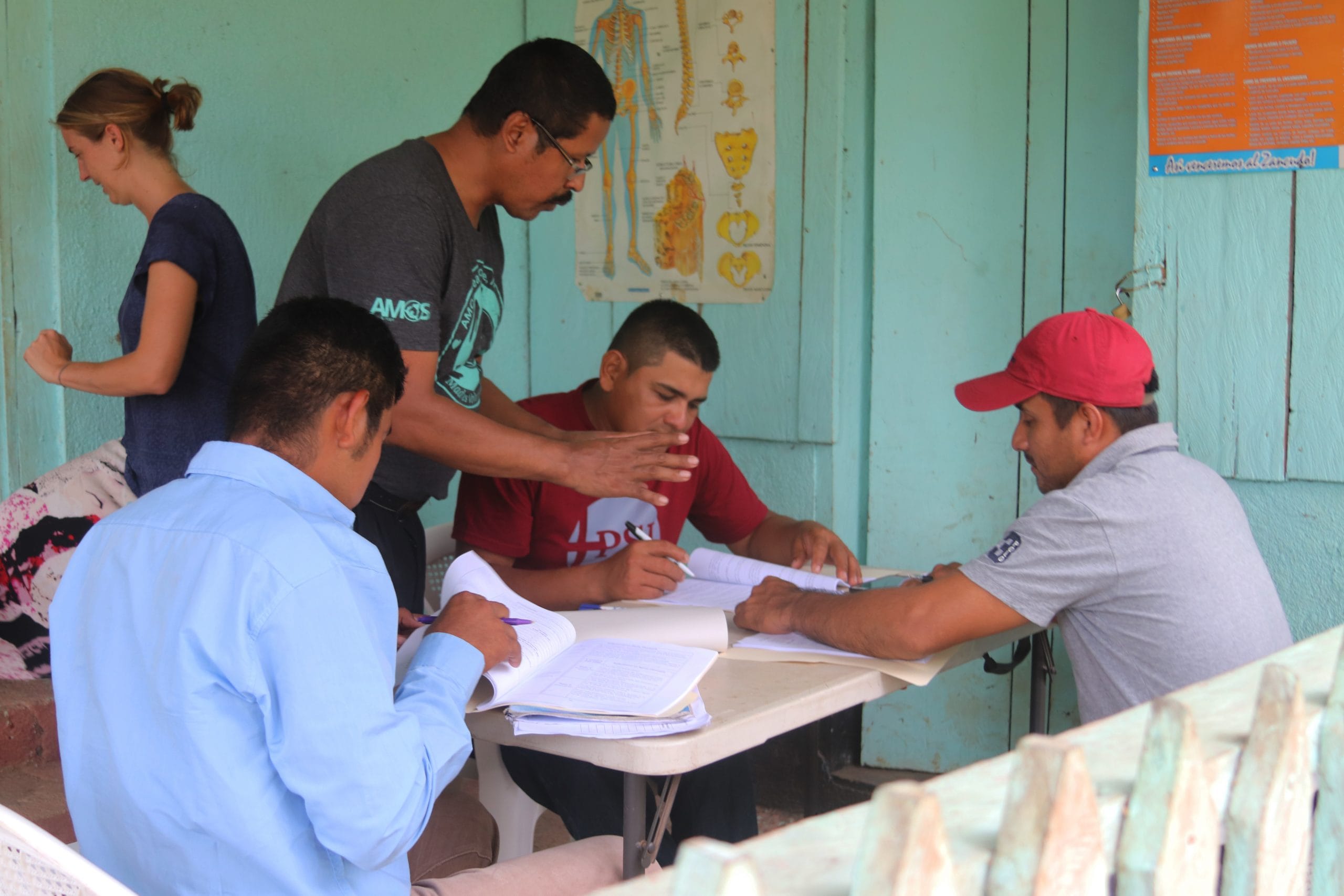 A group of community health workers are sitting at a table as they are trained.