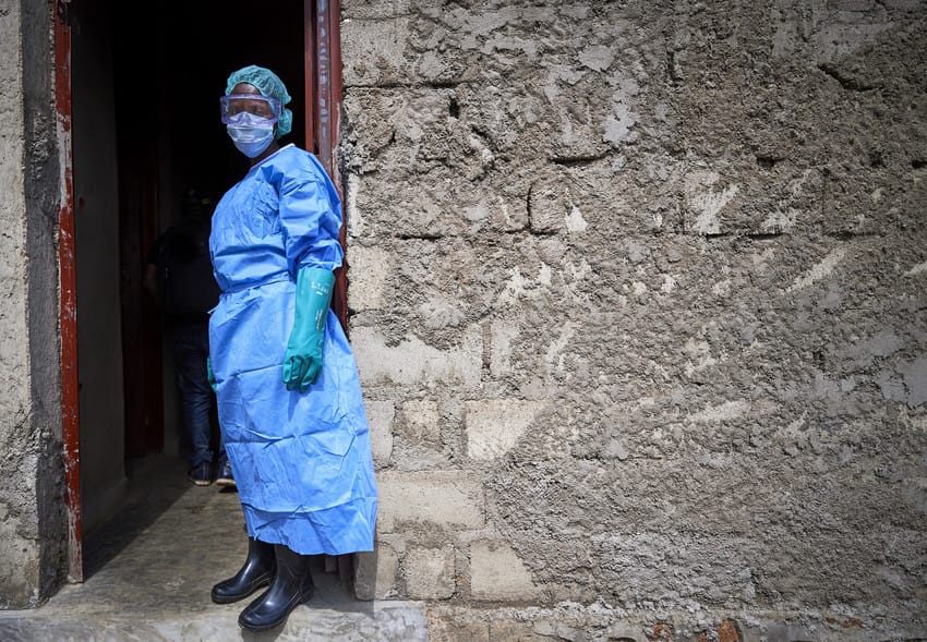 A nurse standing outside a clinic with stone walls wears protective clothing in a clinic in Beni, a city in eastern Democratic Republic of the Congo that was hard hit by the Ebola outbreak that began in 2018.