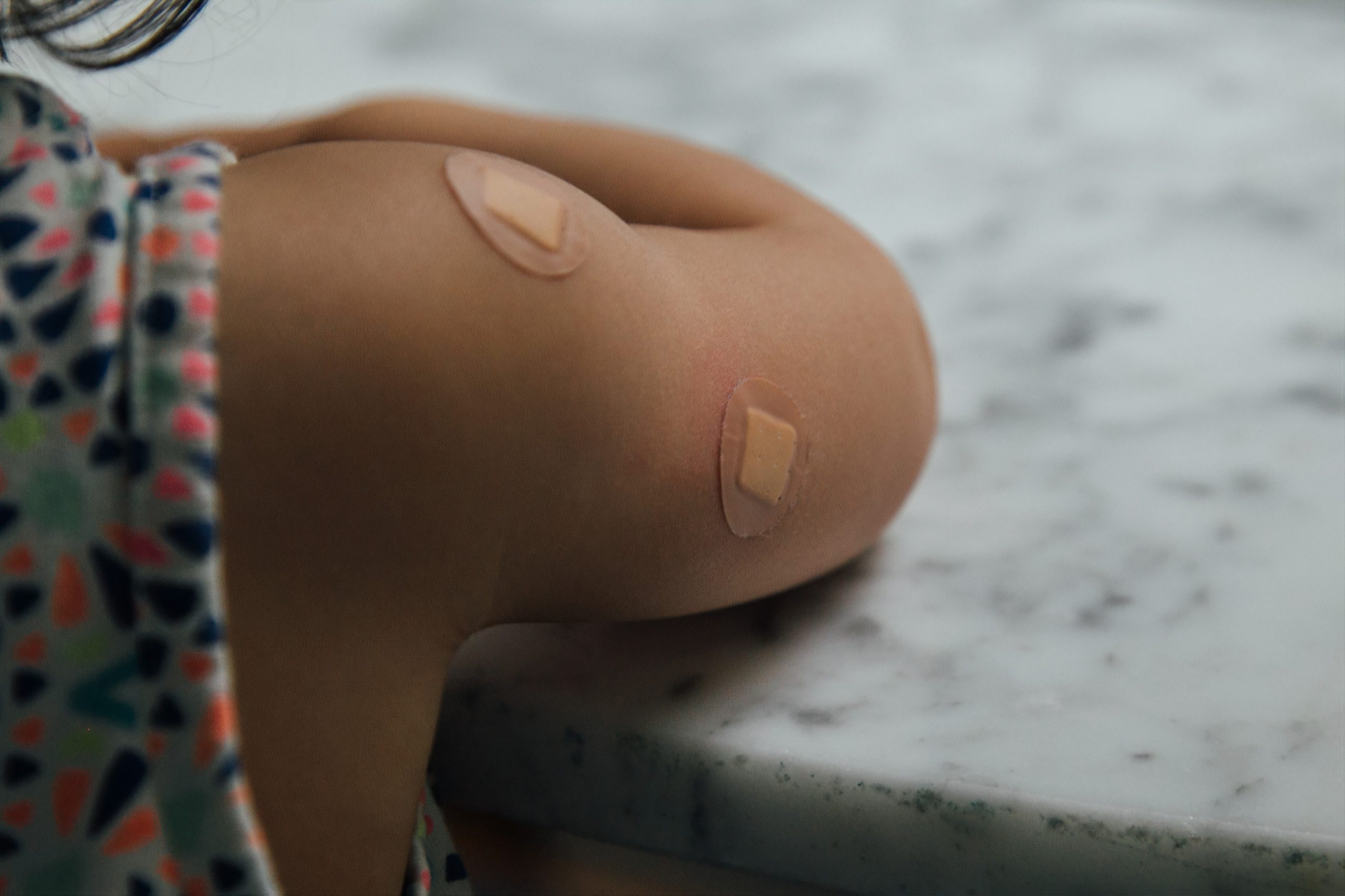 Arm of young child with bandaids following vaccinations