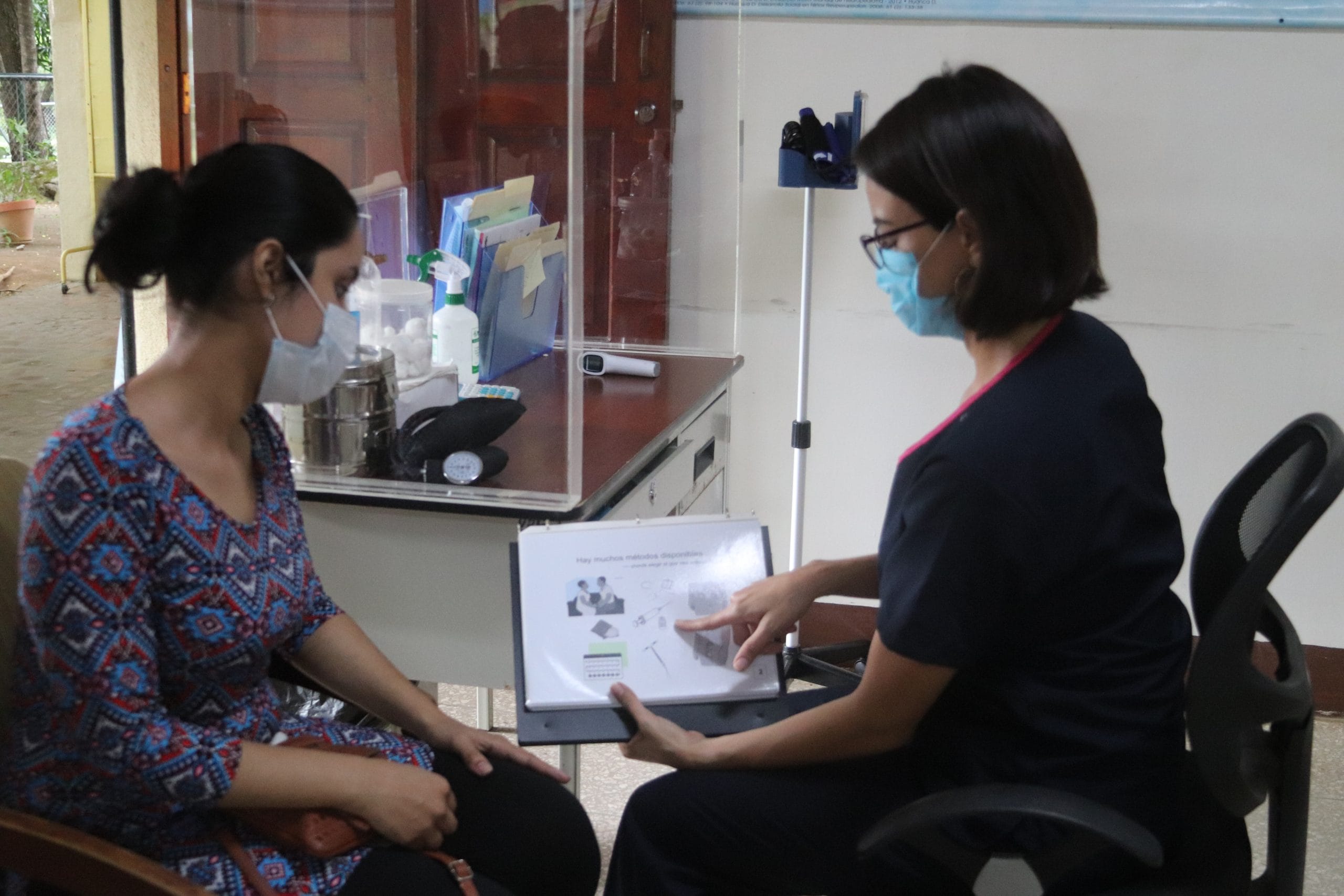 A doctor shows family planning methods in a training book to a patient.