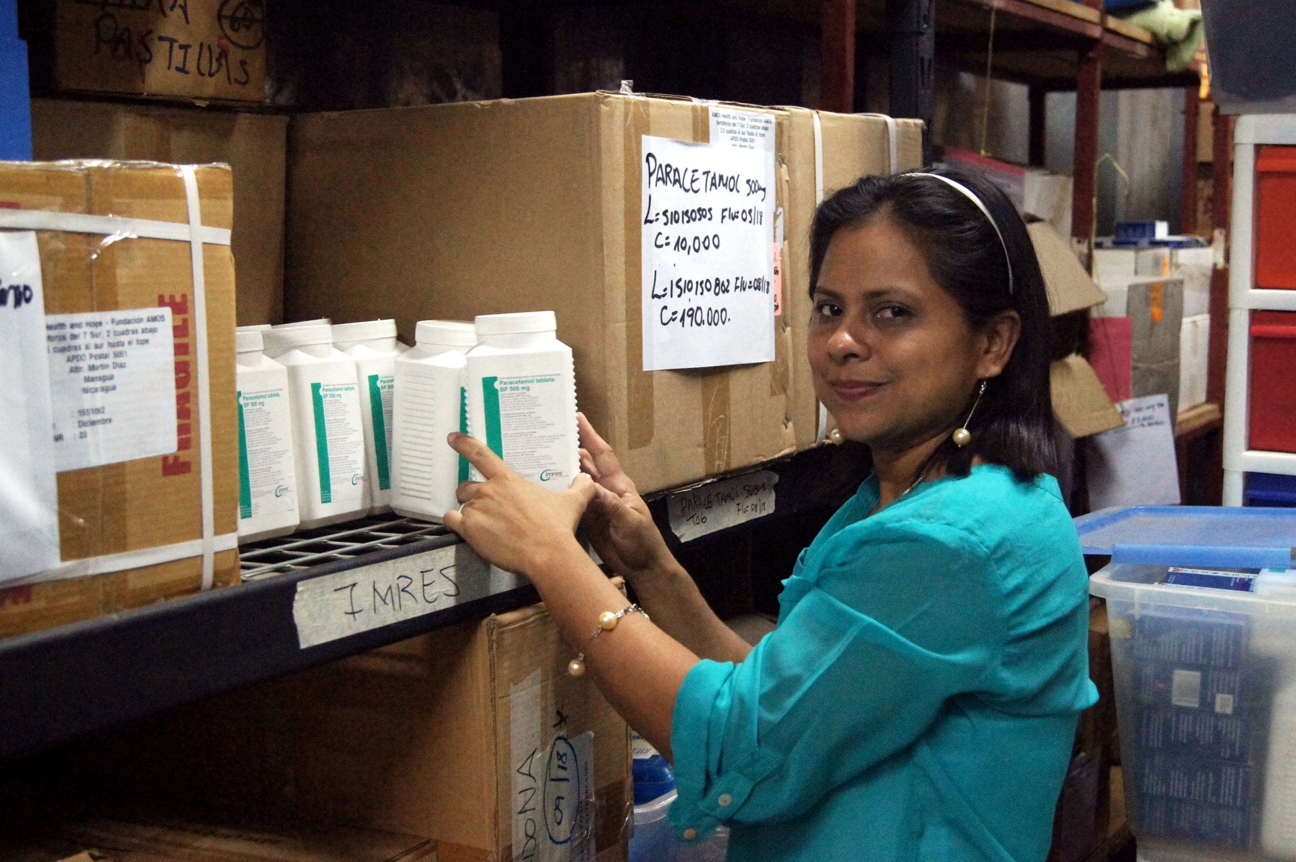 A woman next to pharmaceutical supplies, including family planning supplies.