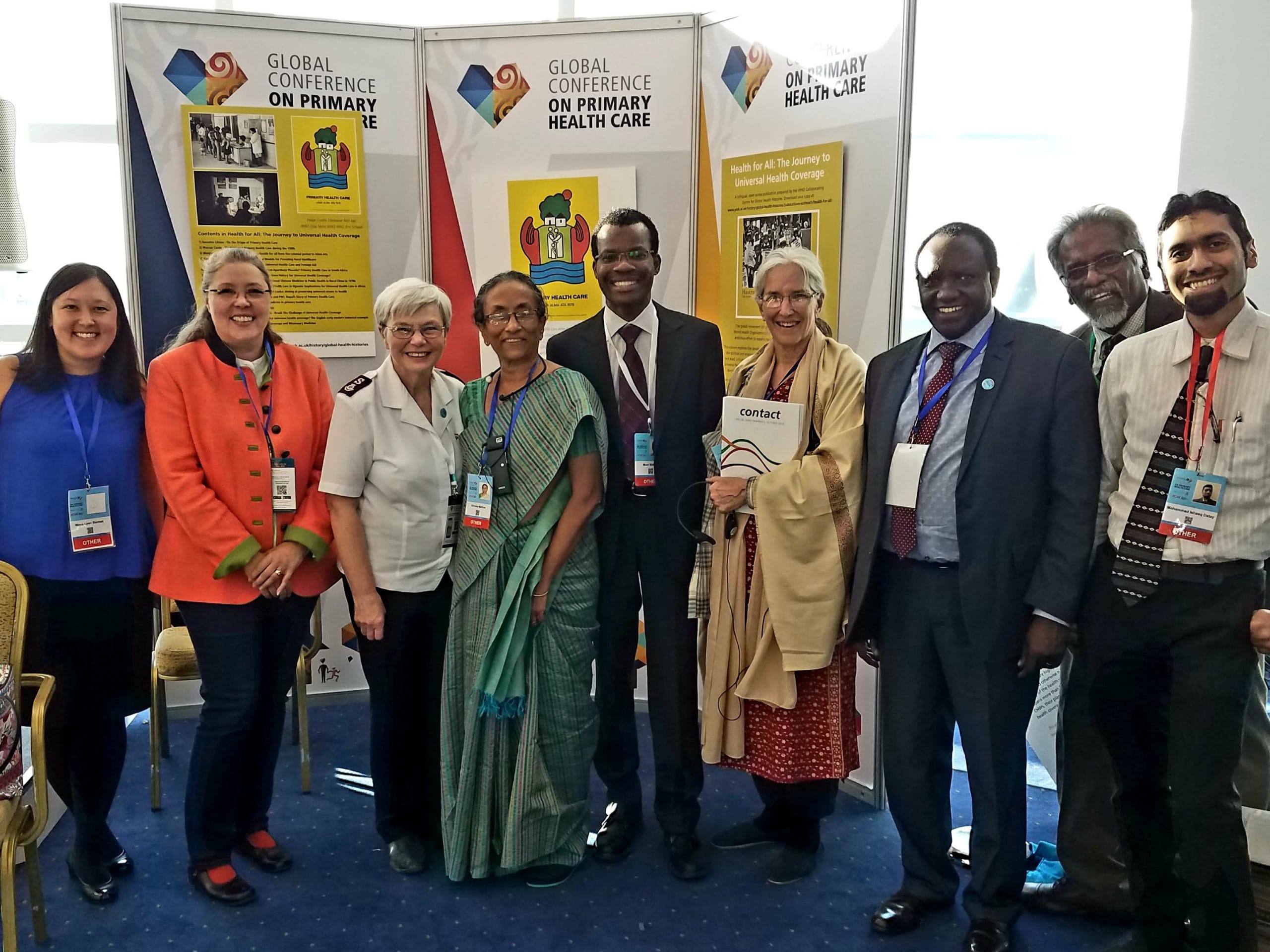 A group of men and women stand in front of banners at the Astana Primary Health Care Conference