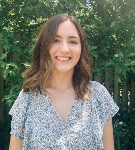 Intern and college student Sarah Scott in front of green foliage