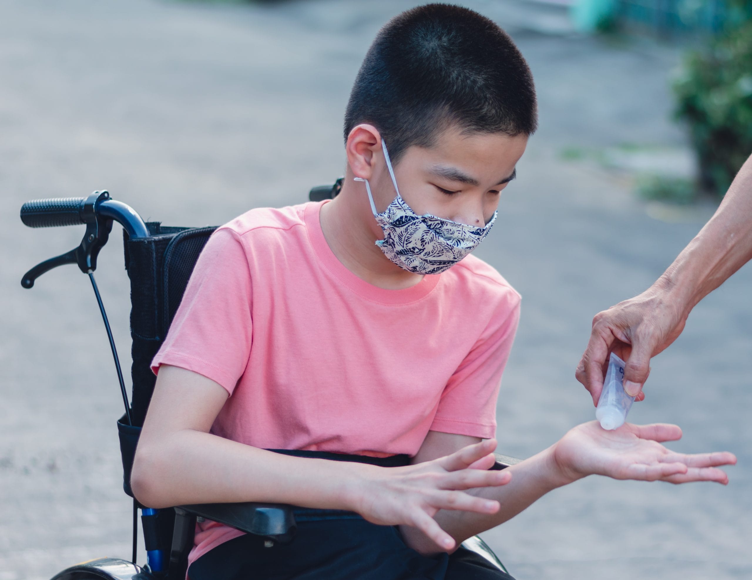 A young boy in a wheel chair receives hand sanitizer