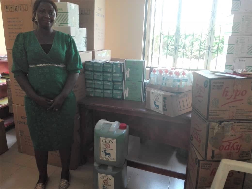 A woman stands next to supplies to mitigate COVID19