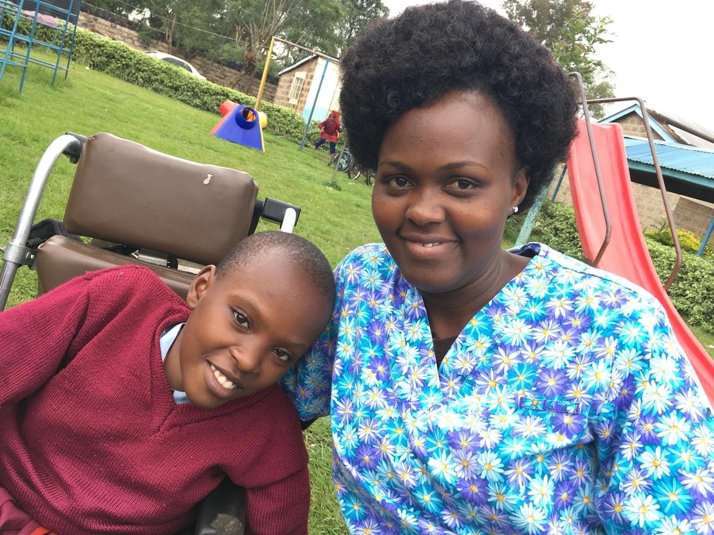 A woman sits next to a young boy in a wheel chair