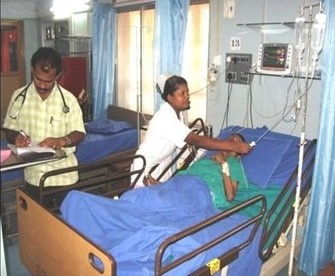 A man and a woman who are health care workers tend to a woman in a hospital bed.