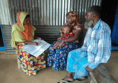 A woman is seated and talks to a couple with a young child