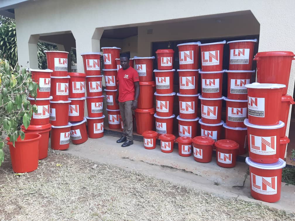 A man stands next to many containers of handwashing solution.