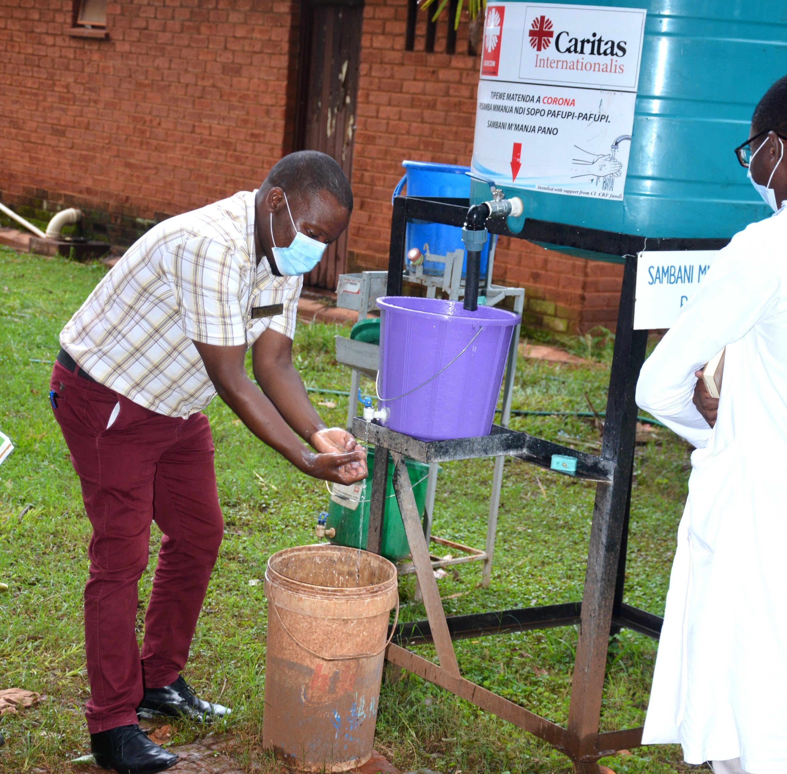 A man washes his hands at an outdoor handwashing facility.