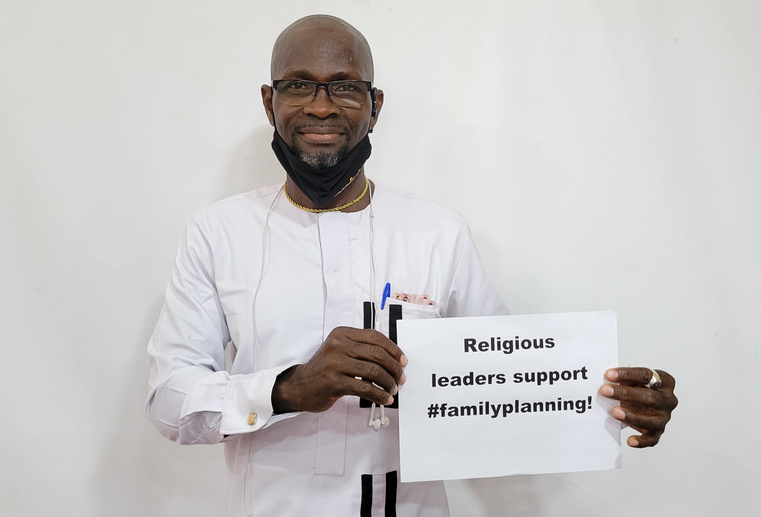 A man holds a sign expressing support for family planning by religious leaders.
