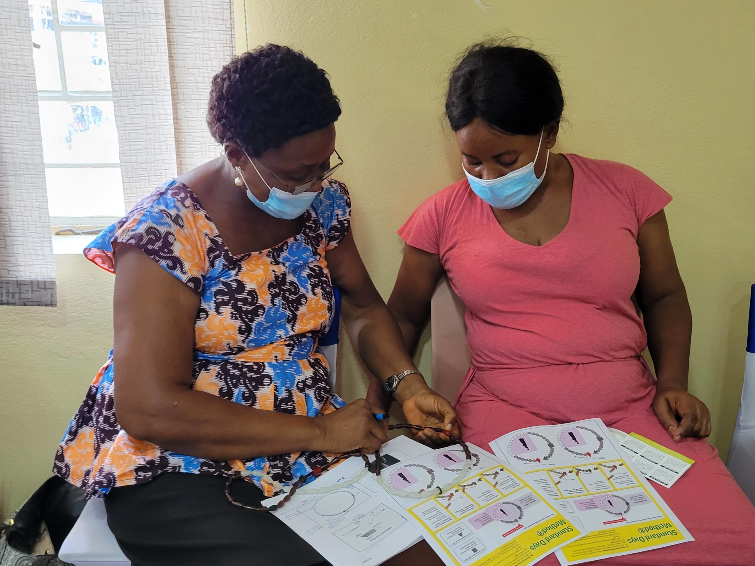 Two women at a health center in Sierra Leone review family planning method instructions.